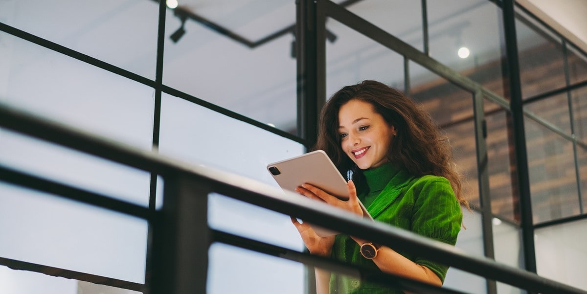 woman in green shirt office looking at tablet